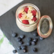 Topshot von Glas gefüllt mit Chiapudding, Himbeeren und Mandelplättchen