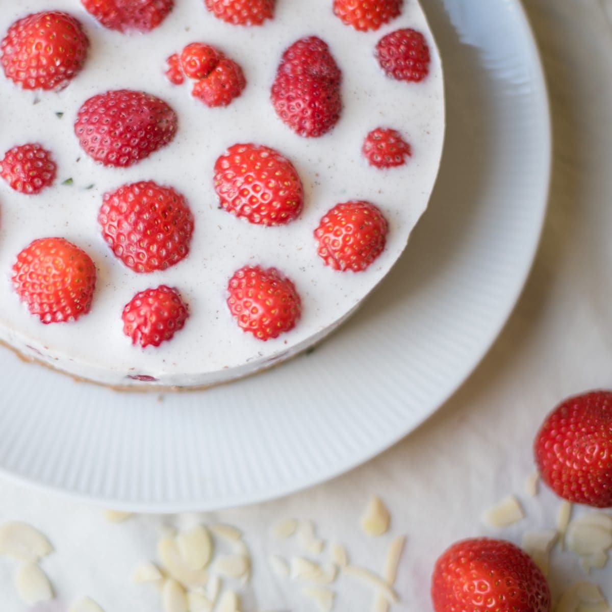 Topshot von rundem Kuuchen mit weißer Panna Cotta und ganzen Erdbeeren