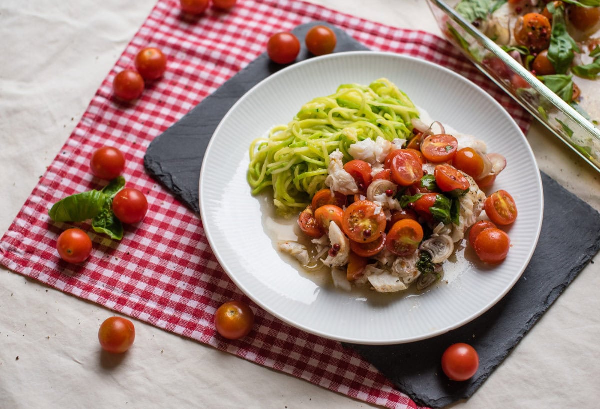 Teller mit Kabeljau aus dem Ofen, Zucchininudeln und halbieren Kirschtomaten