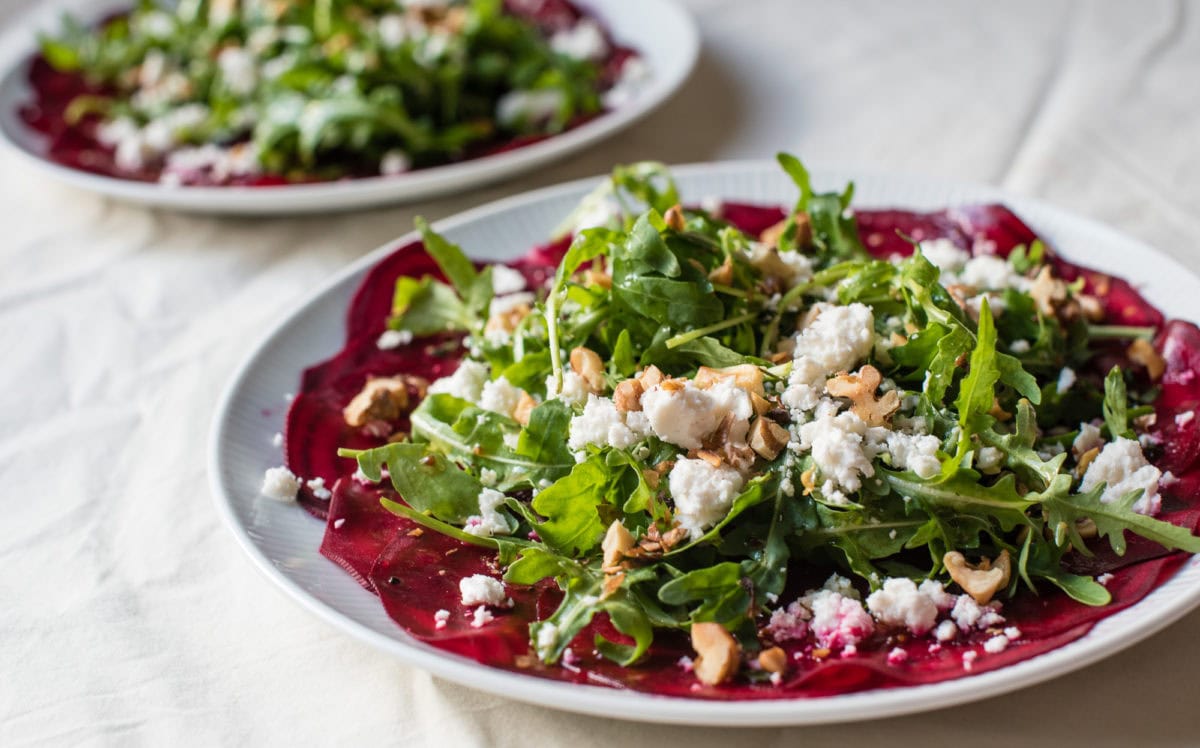 seitliche Ansicht von weißem Teller mit rote Bete Carpaccio, Rucola und Ziegenkäse