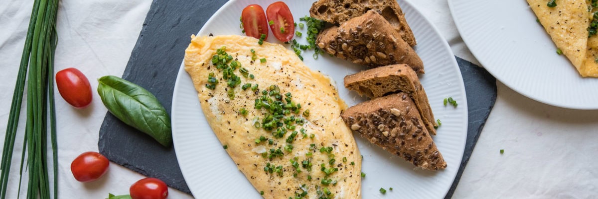 Topshot von Omelette mit Brotscheiben, Kräutern und Tomaten angerichtet