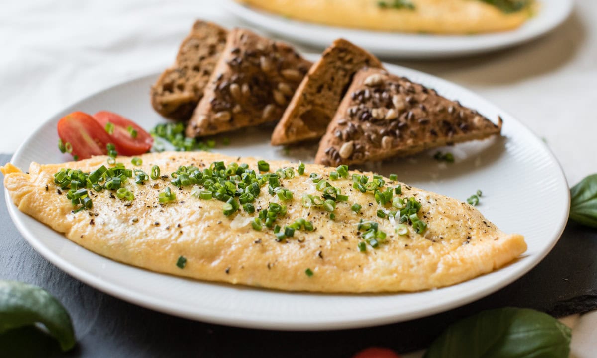 Omelette mit Schnittlauch und Brotscheiben auf Teller