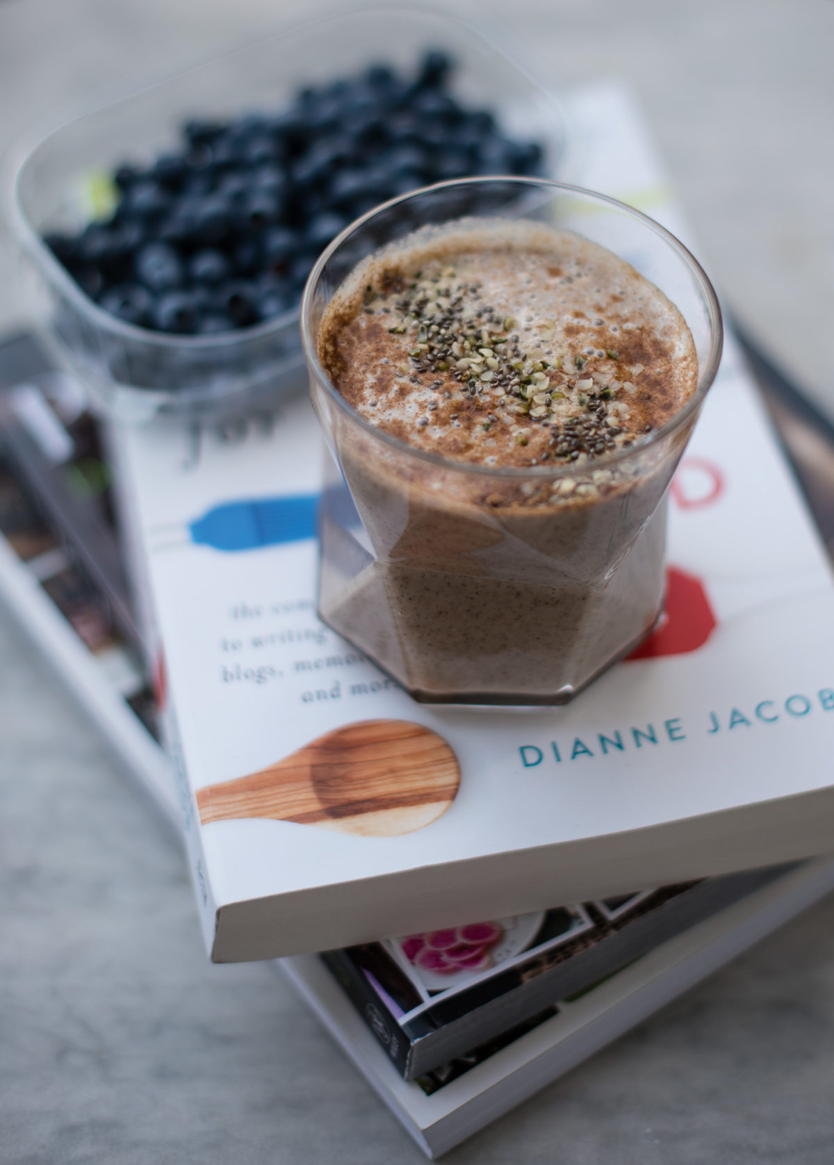 Glas gefüllt mit Iced Chai Latte auf Bücherstapel mit Blaubeeren im Hintergrund