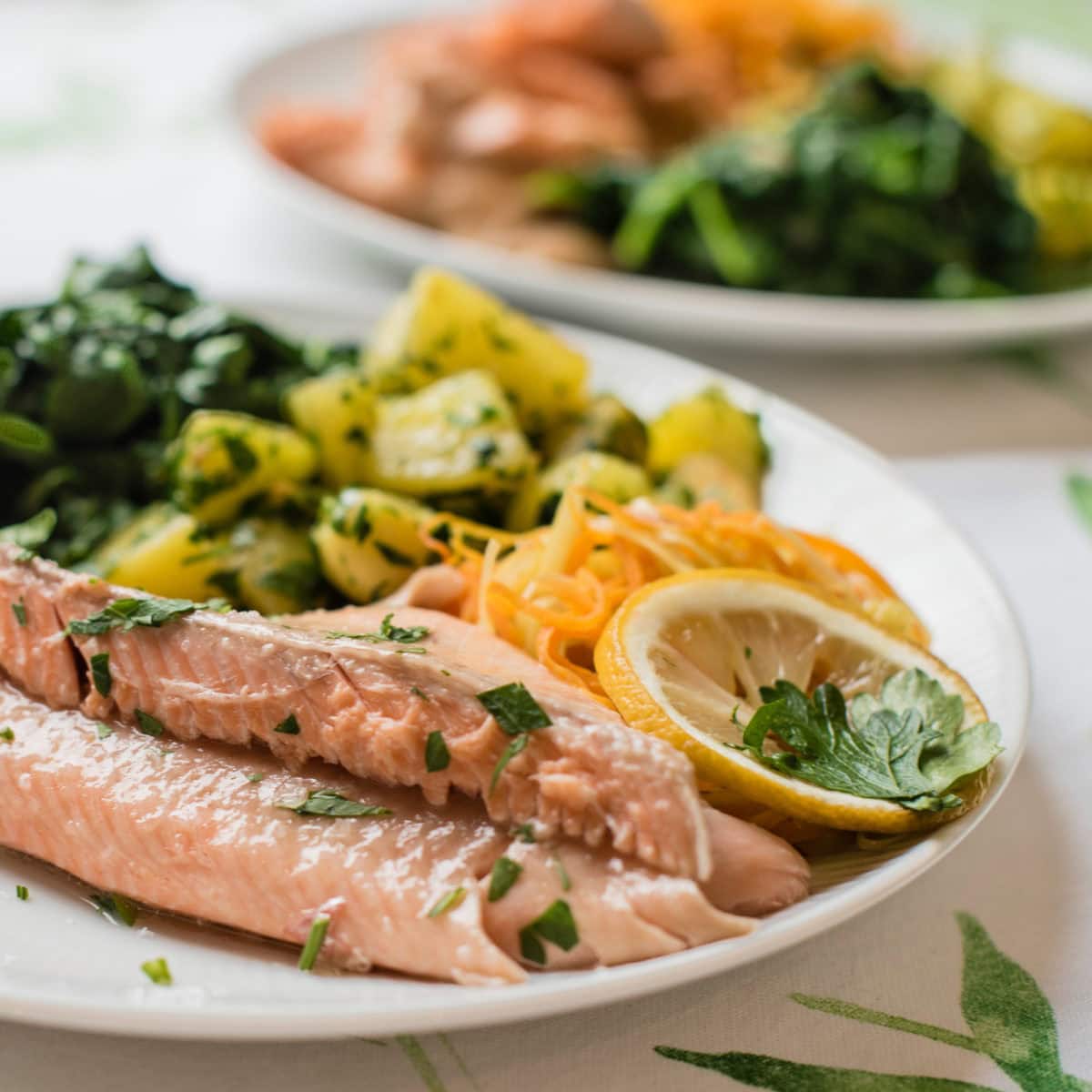 Teller seitlich fotografiert mit Fischfilet und Beilagen