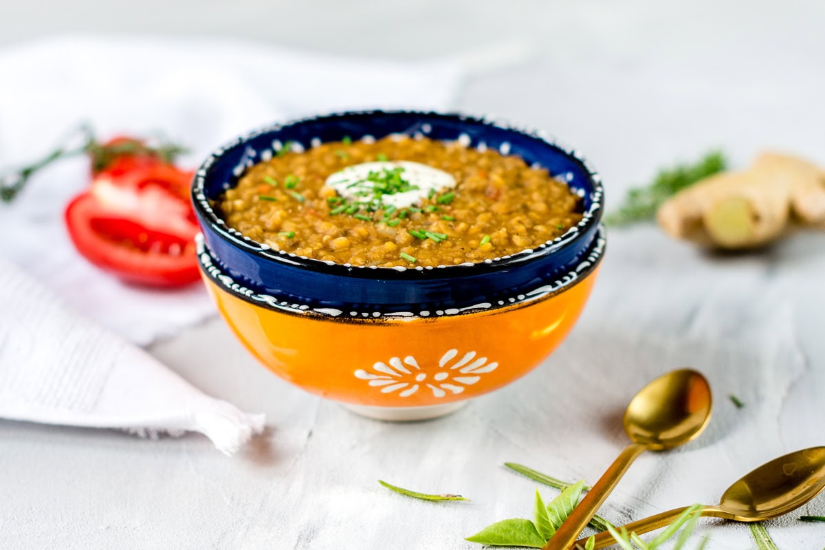 Rote Linsensuppe in bunter Schüssel auf grauem Untergrund