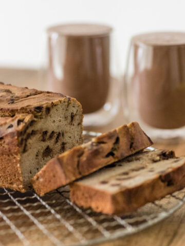 aufgeschnittenes Bananenbrot auf Rost vor zwei Gläsern