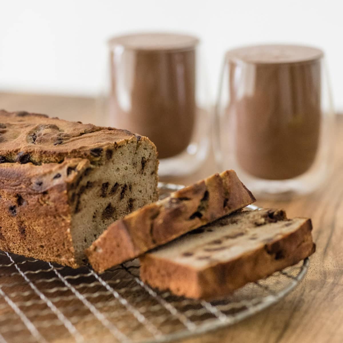 aufgeschnittenes Bananenbrot auf Rost vor zwei Gläsern