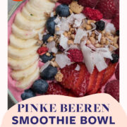 Topshot von pinker Smoothie Bowl mit gemischten Beeren und Kokoschips getoppt
