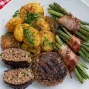 Frikadellen mit Speckbohnen und Kartoffeln auf weißem Teller