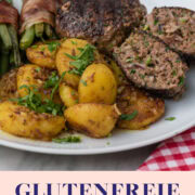 Teller mit Frikadellen, Kartoffeln und Speckbohnen auf weißem Teller.