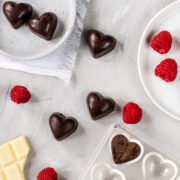 Schokoladenpralinen in Herzform, frische Himbeeren und weiße Schokolade