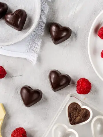 Schokoladenpralinen in Herzform, frische Himbeeren und weiße Schokolade