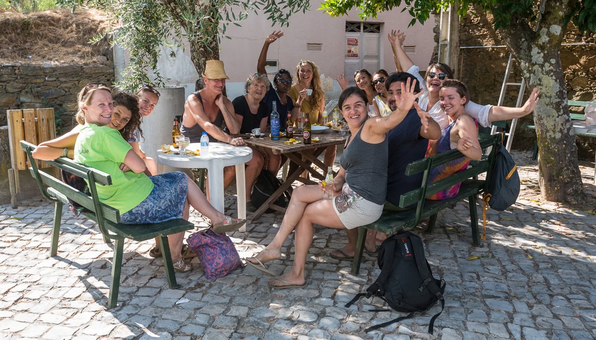 Menschengruppe in Innenhof an Gartentisch sitzend und wickend