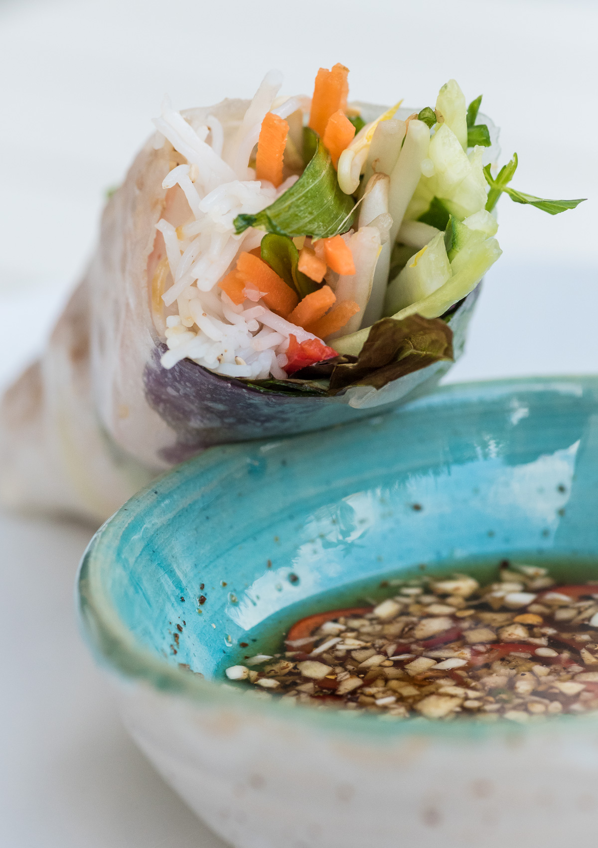 Pinne das Foto, um das Rezept für vietnamesische Sommerrollen zu speichern! Mit Gemüse gefüllte Sommerrolle mit einer Schale Sojasauce.
