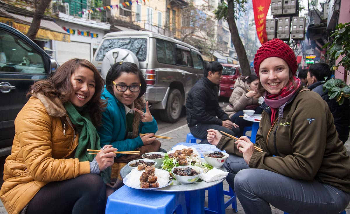 Pinne das Foto, um das Rezept für vietnamesische Sommerrollen zu speichern! Drei Frauen an kniehohem, gedeckten Tisch essend