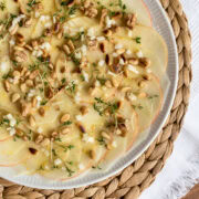 Topshot von weißem Teller mit Kohlrabi -Apfel-Carpaccio, getoppt mit Pinienkernen und Kresse