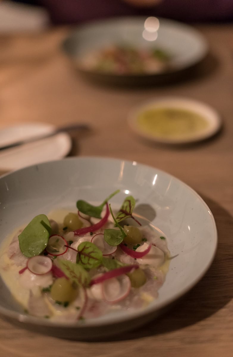 Teller mit Radieschen, Feldsalat und verschiedenem Gemüse auf Holztisch