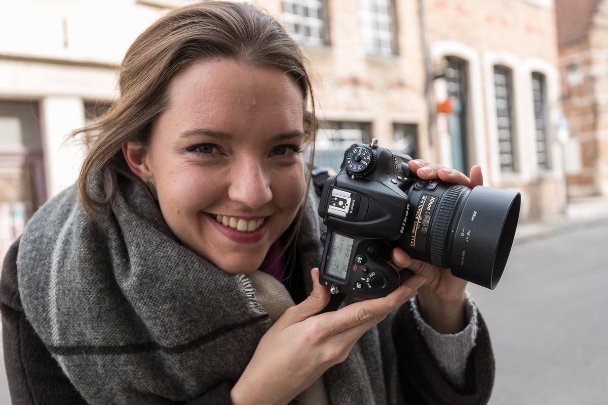 Portrait von lachender Frau mit Kamera in den Händen