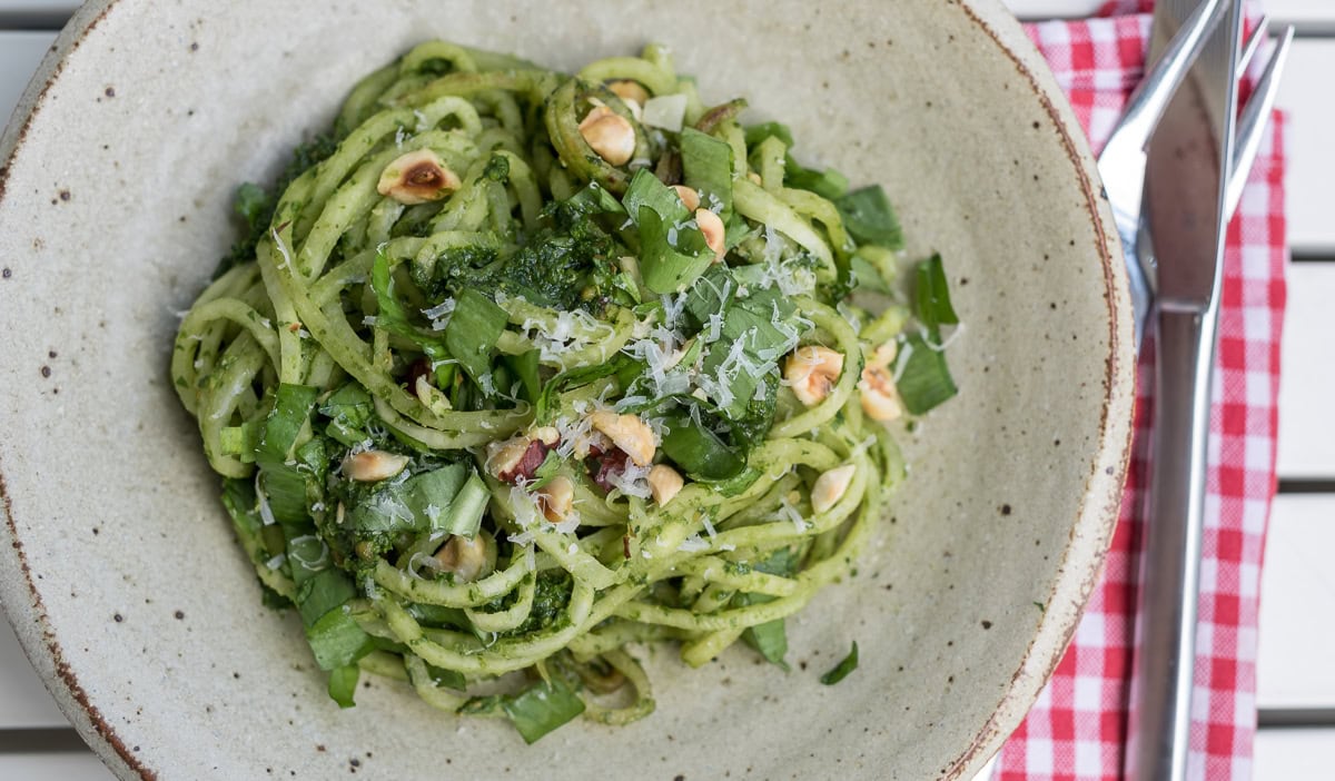 Vegetarisches Rezept für den Frühling mit Nudeln, Bärlauchpesto und Walnüssen auf einem Teller.