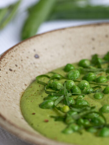 Seitliche Ansicht von Suppenteller mit grüner Suppe und Erbsen