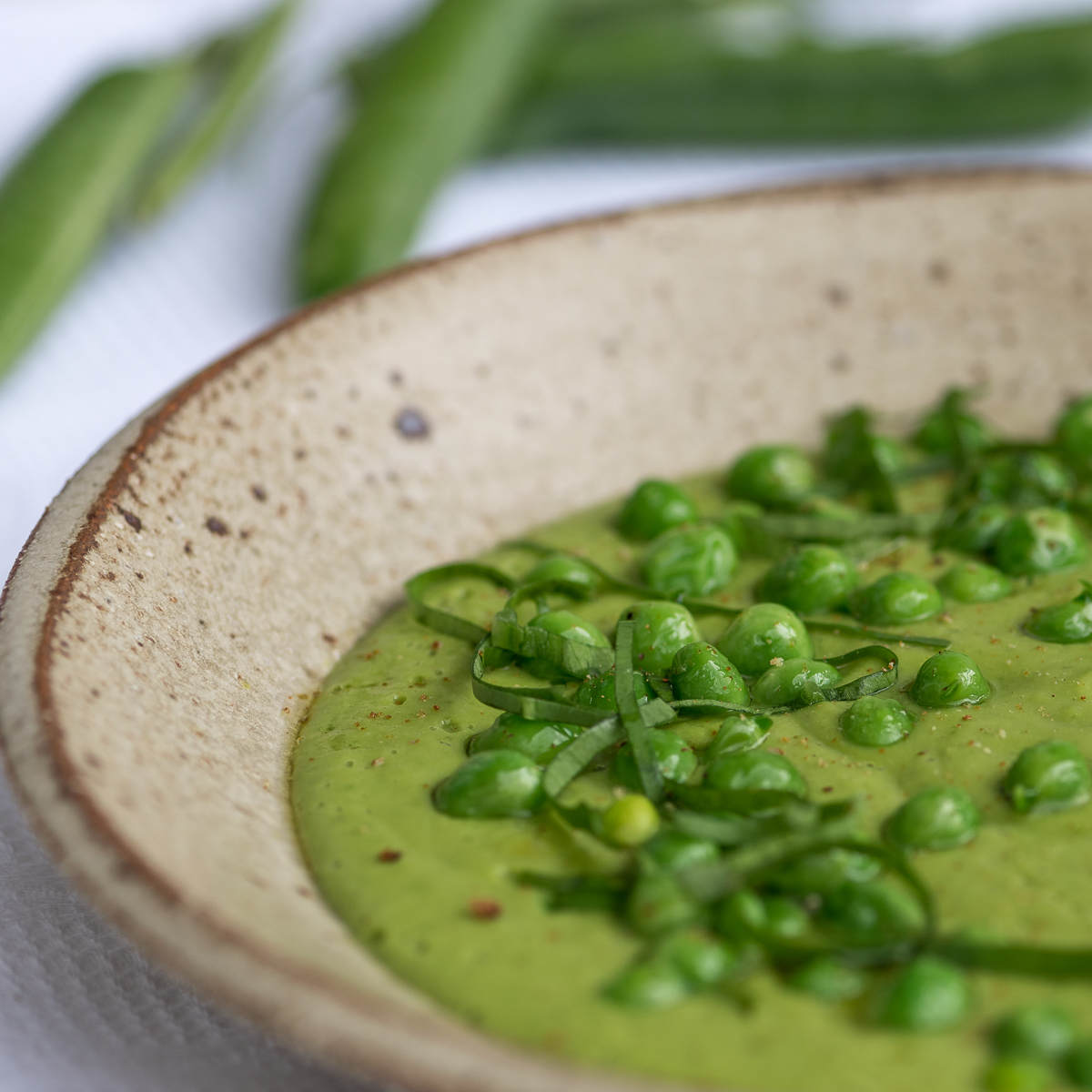 Seitliche Ansicht von Suppenteller mit grüner Suppe und Erbsen