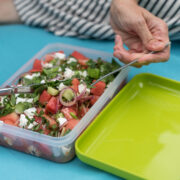 Brotdose mit bunten Salat und Händen mit Messer und Gabel