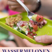Hand hält knallgrünen Teller mit buntem Salat darauf
