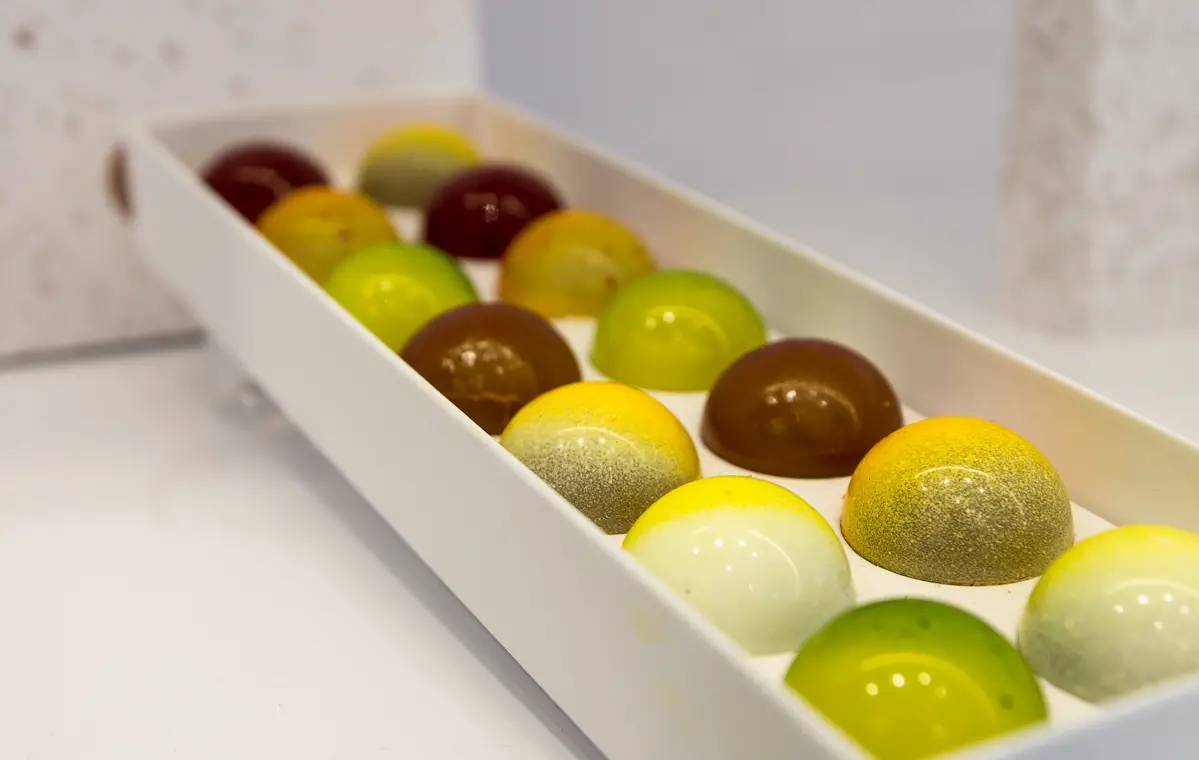 grün, gelb und braune belgische Schokoladenkugeln in Reihen angeordnet