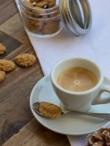 Espresso in weißer Tasse und mit kleinem Teelöffel und Amarettini Keks