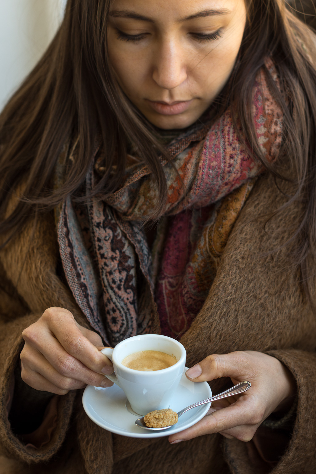 Frau hält Espresso mit kleinem Amarettini in der Hand