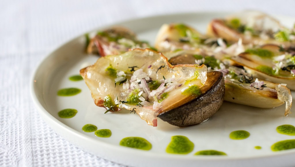 Gegrillter Kräutersaitling mit grüner Sauce auf weißem Teller