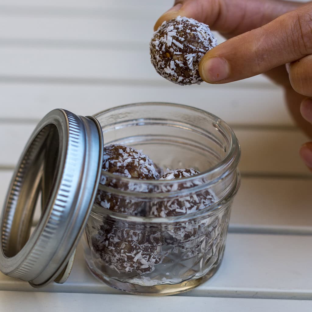 Snackkugel mit Kokosraspel wird aus kleinem Glas genommen