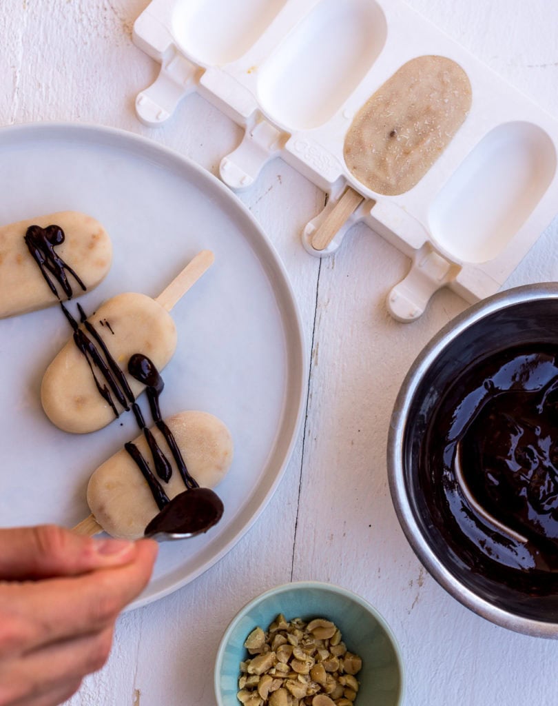 Pinne das Foto, um dir meine Rezeptsammlung für gesundes Eis zum selber machen zu speichern! Topshot von selbstgemachtem Erdnusseis, das mit geschmolzener Schokolade verziert wird.