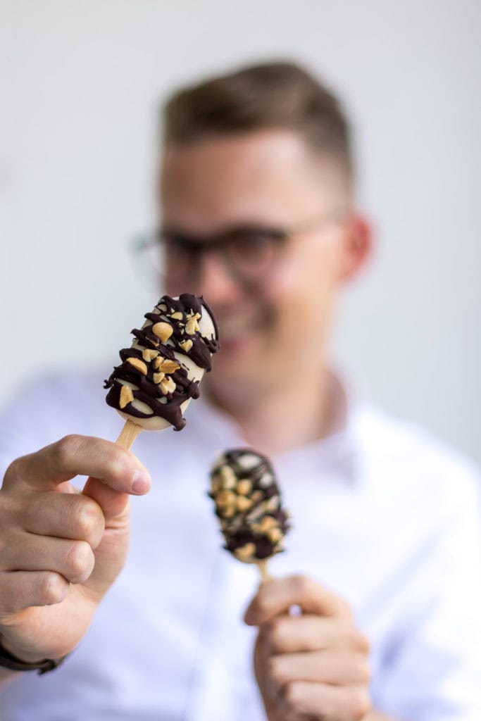 Mann hält zwei Eis am Stiel in die Kamera