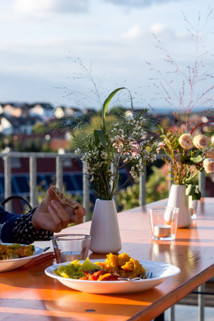 Tisch auf Terrasse mit Blumenvasen und gefüllten Tellern