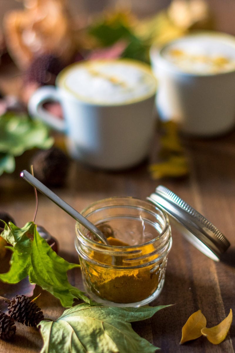 Kurkuma Latte Mix als Pulver im Glas und mit Blättern dekoriert
