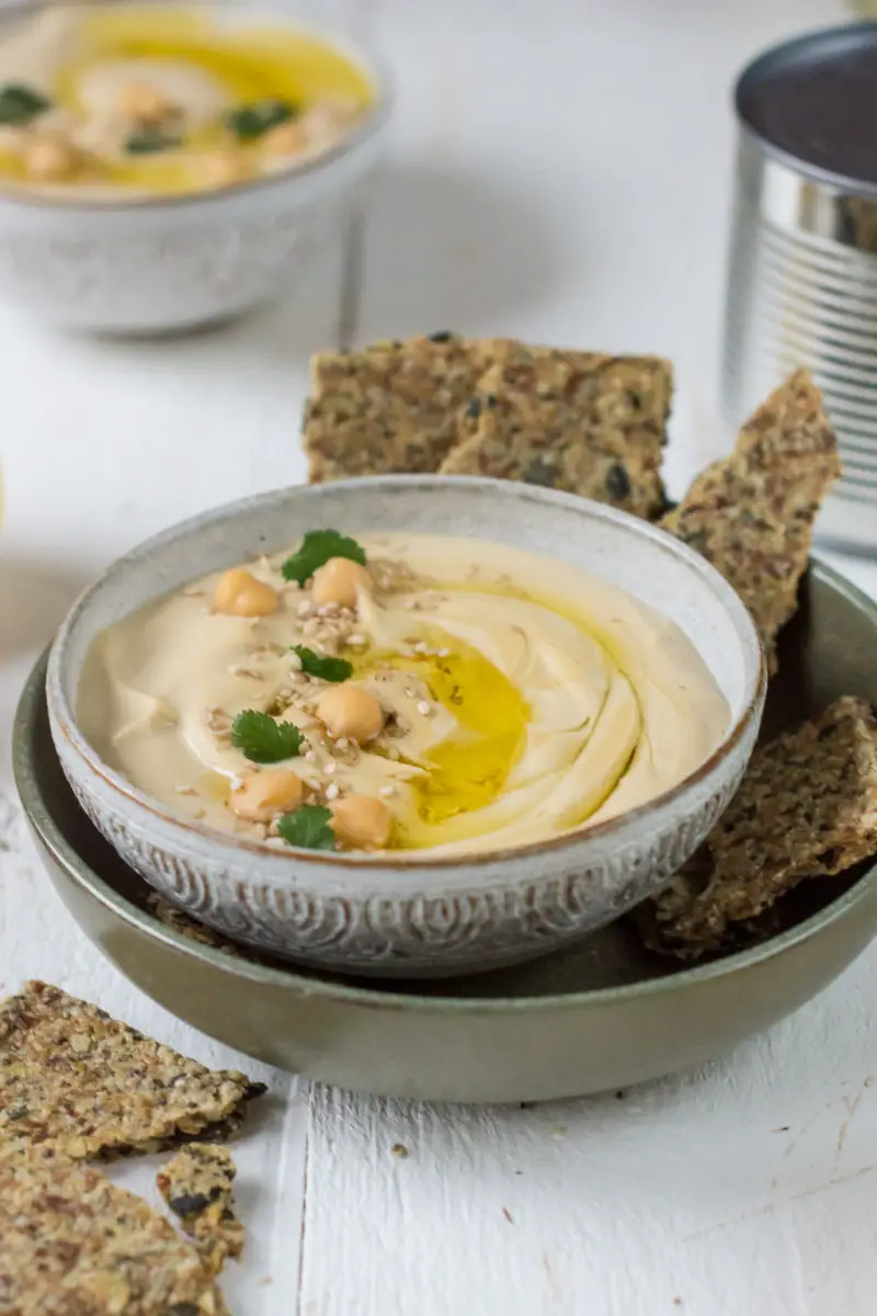 Hummus in Schüssel mit Kichererbsen und Knäckebrot dekoriert