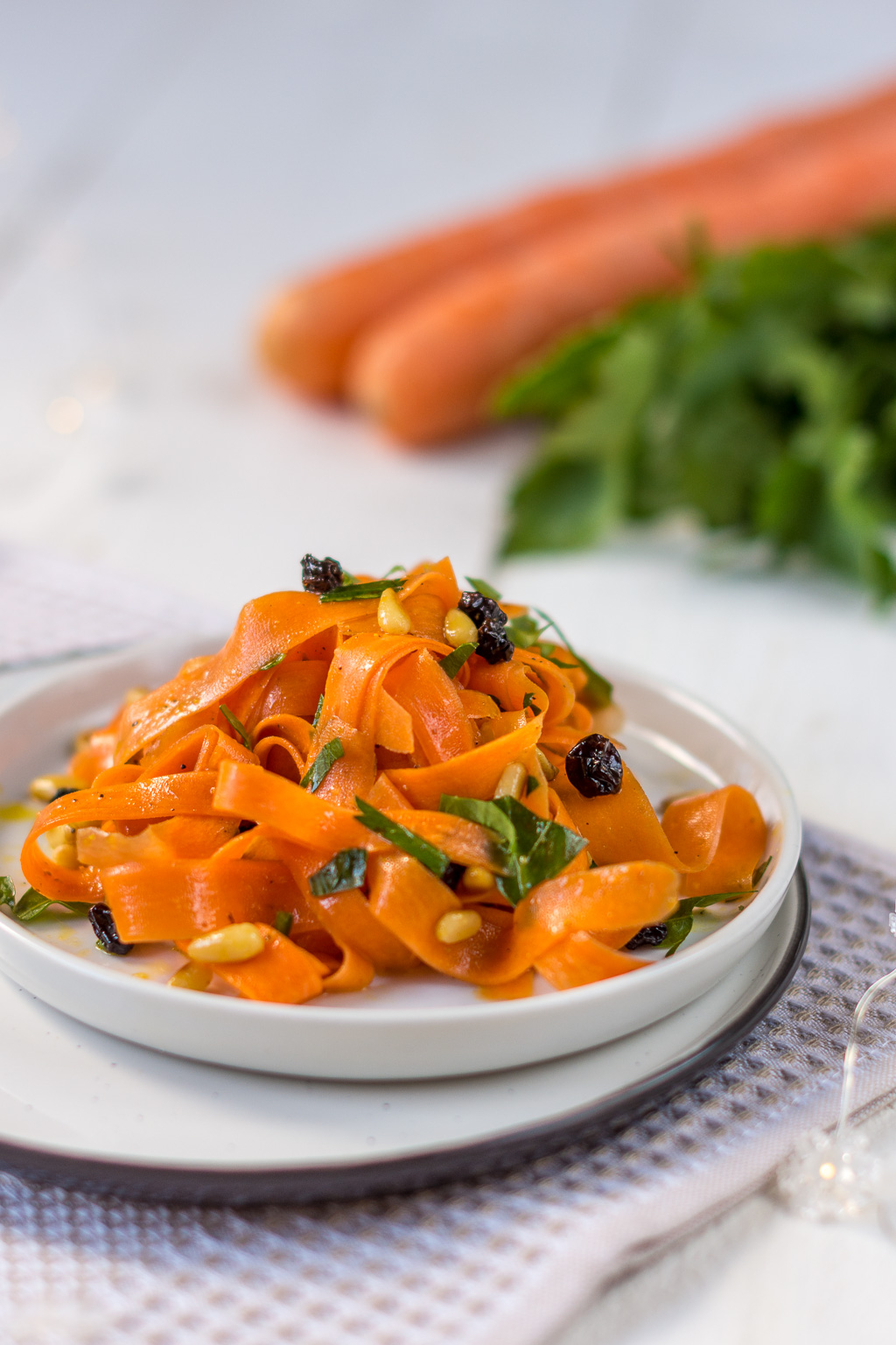 Karottensalat mit Rosinen auf Teller angerichtet und mit einem Bund Karotten dekoriert