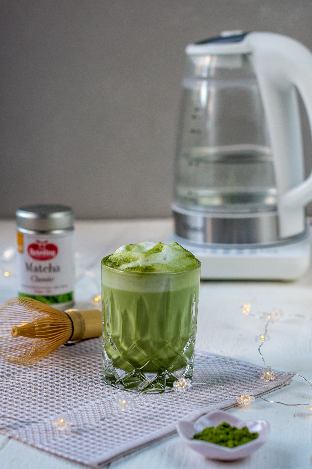 Matcha Latte im Glas vor Wasserkocher