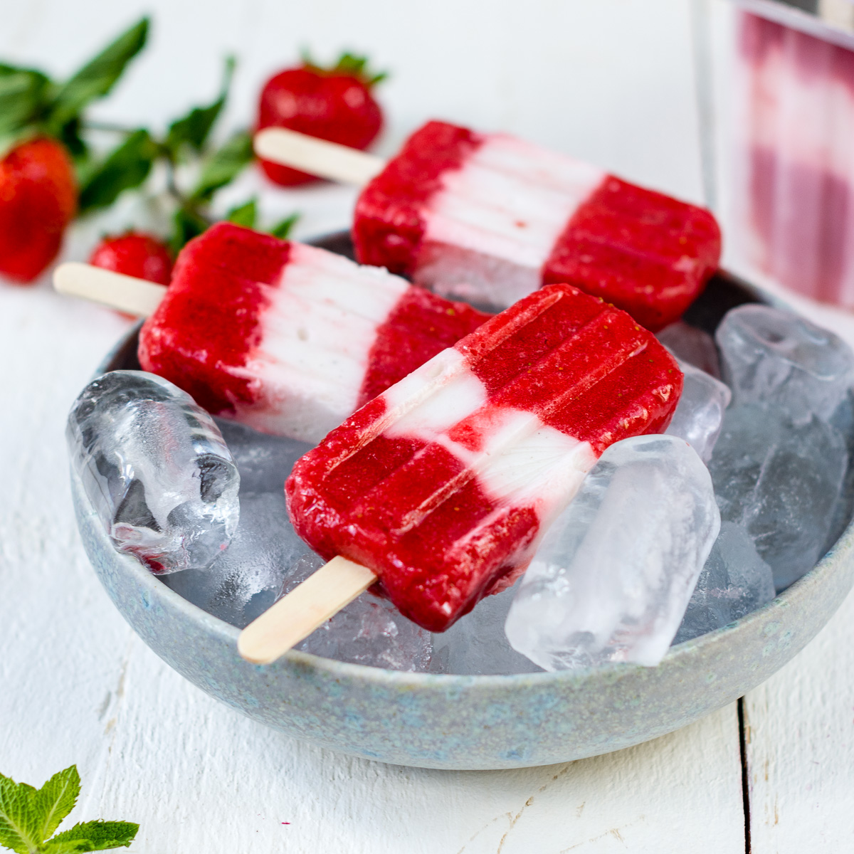 Erdbeer Joghurt Popsicles in Schale mit Eiswürfeln.