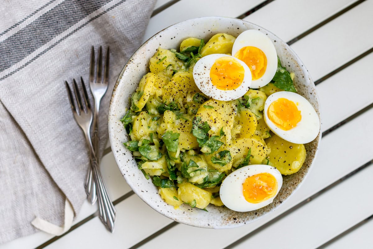 Kartoffelsalat mit vier Eierhälften und Petersilie und zwei Gabeln