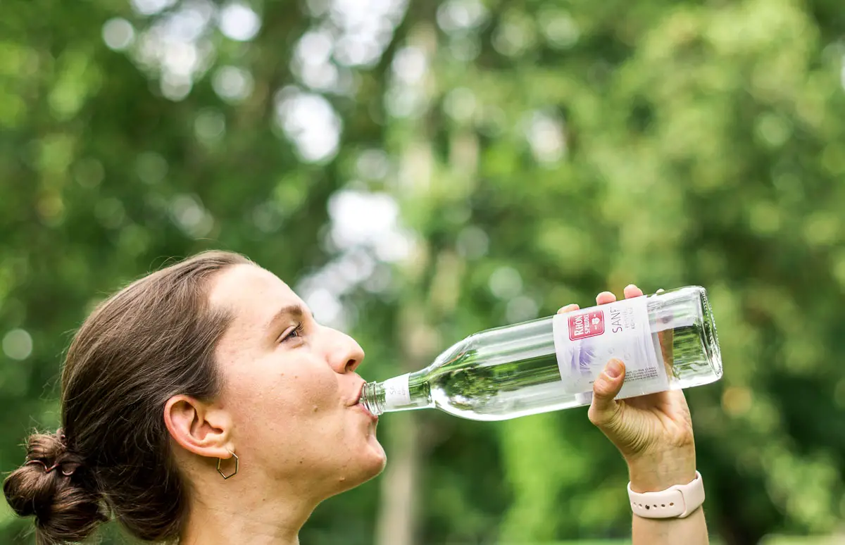 Frau trink Wasser aus Glasflasche