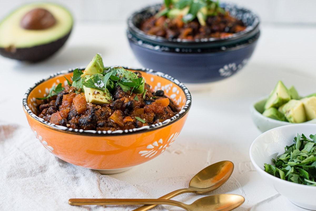 seitliche Ansicht von Chili in orangefarbener Schale, mit Petersilie und Avocado dekoriert