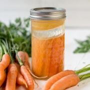 Schraubglas mit fermentierten Karotten gefüllt und frischen Karotten dekoriert