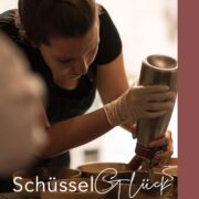 Frau beugt sich über eine Anrichte mit Schüsseln und hält eine Flasche in der Hand.