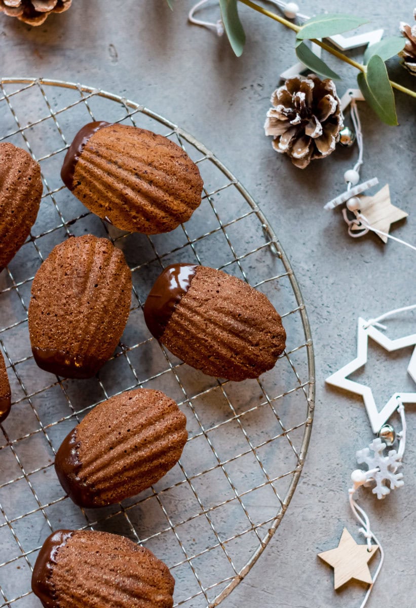 Topshot von Kuchengitter mit Madeleins mit Schokoladenüberzug.