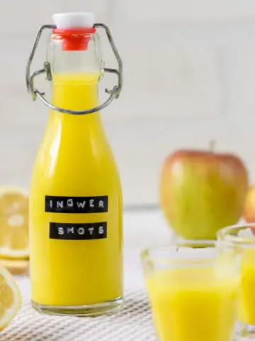 Ingwer Shot Bügelflasche, zwei Ingwer Shot Gläser, Apfel, Zitrone und Ingwer.