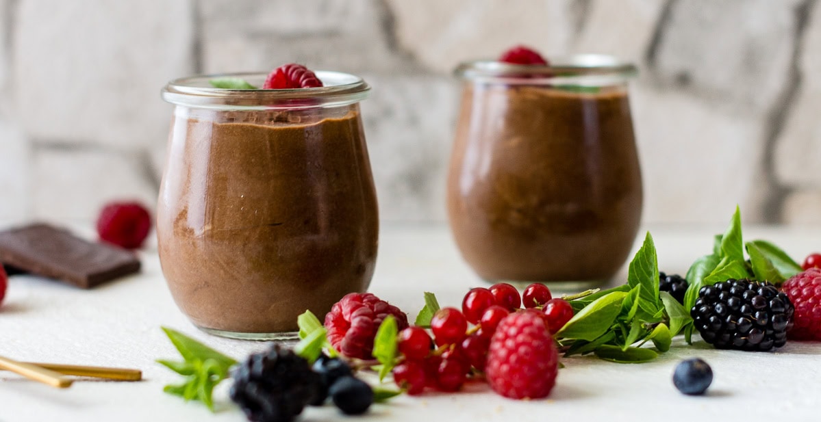 Speichere dieses Foto, um das Rezept für Mousse au Chocolat zu sichern! Mousse au Chocolat Schokoladendessert in zwei Gläsern und mit Beeren garniert.