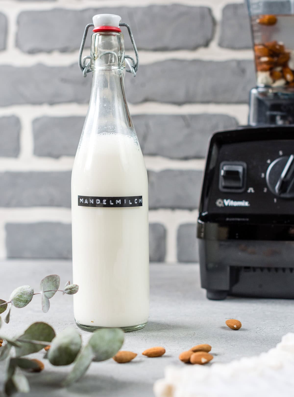 Pinne das Foto, um das Rezept für selbstgemachte Mandelmilch zu speichern! Selbstgemachte Mandelmilch in Bügelflasche vor Mixer