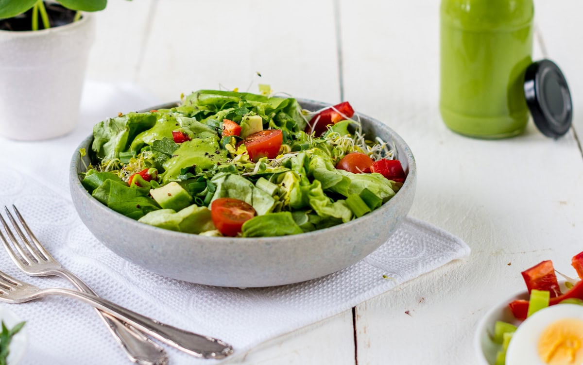 Pinne das Foto, um das Rezept für das Avocado Kräuter Dressing zu speichern! Schüssel mit grünem Salat, Tomaten und Sprossen.